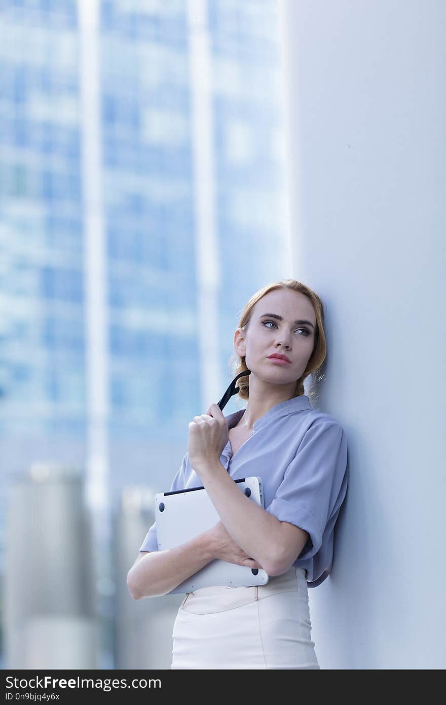 Sad girl standing with a laptopin the middle of the business word. A woman fired from her job