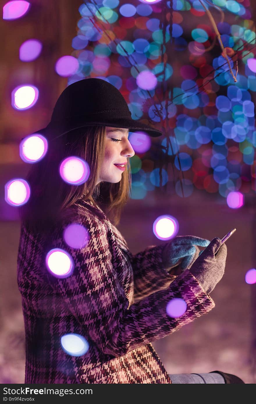 Young girl sending sms christmass wishes during winter alone in