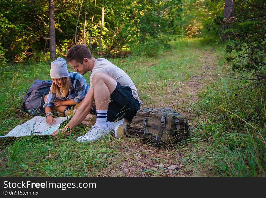 Young couple examining the map inside the forest. Hiking concept