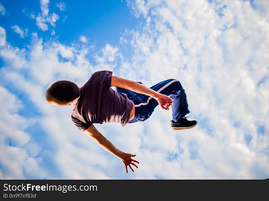 Parkour man exercising parkour below blue sky. Parkour man exercising parkour below blue sky