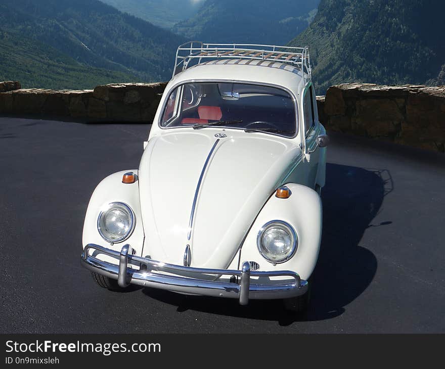 Volkswagen Beetle parked in front of tall mountains in the distance. Volkswagen Beetle parked in front of tall mountains in the distance.