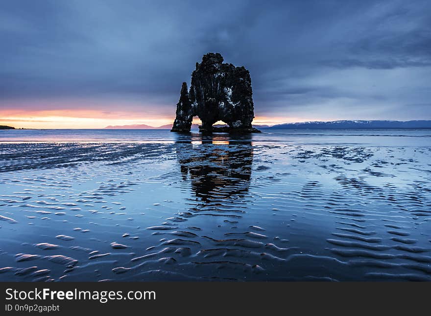 Hvitserkur is a spectacular rock in the sea on the Northern coast of Iceland. Legends say it is a petrified troll. On this photo Hvitserkur reflects in the sea water after the midnight sunset.