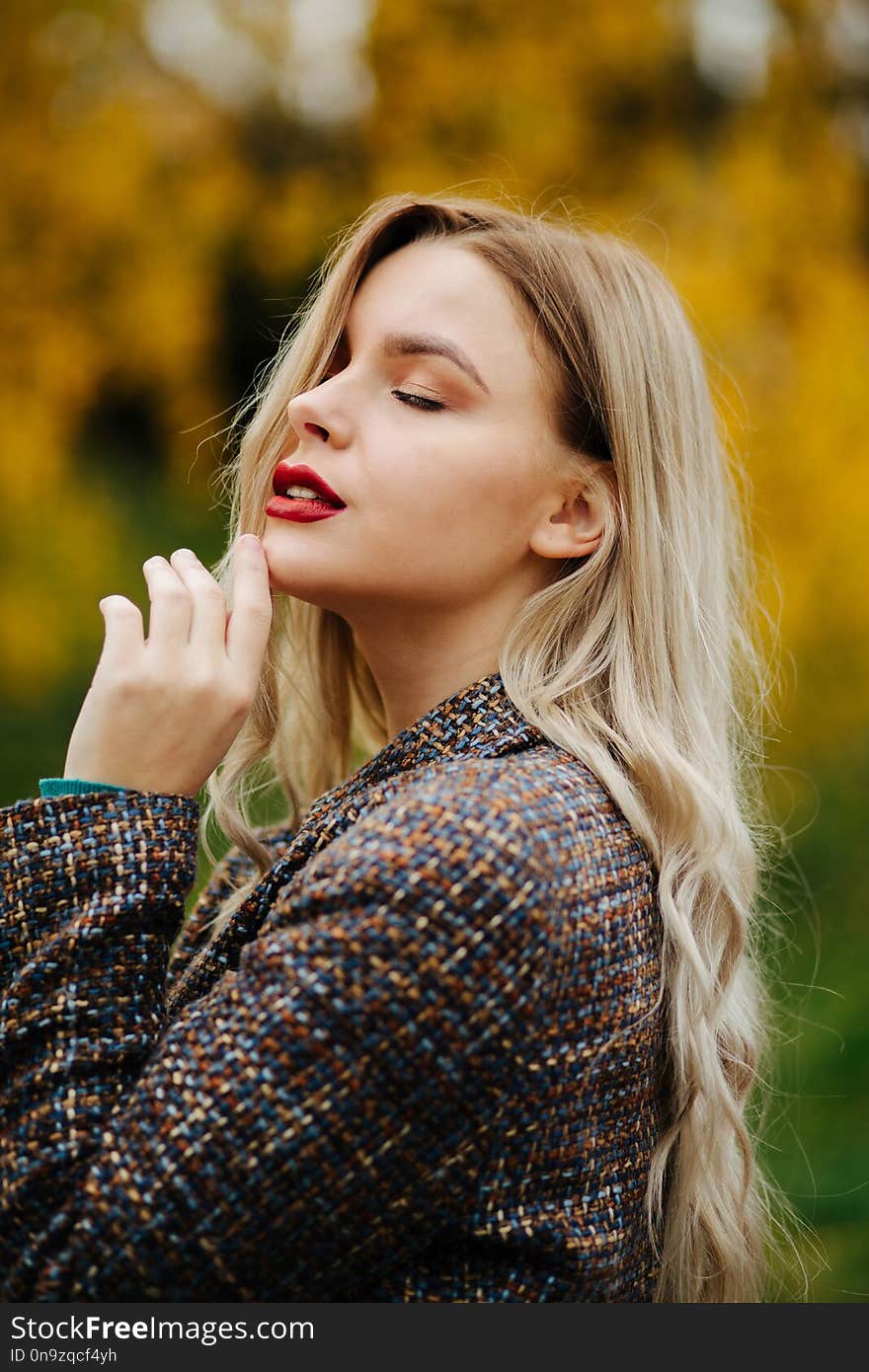 Romantic young woman with closed eyes posing at the autumn park