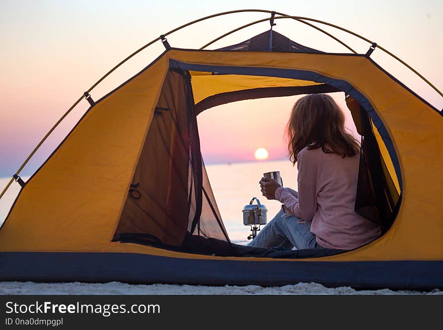 Happy weekend by the sea - girl in a tent on the beach at dawn. Ukrainian landscape at the Sea of Azov, Ukraine