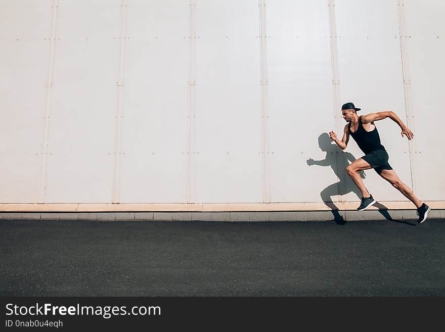 Young man runner running along wall with copy space