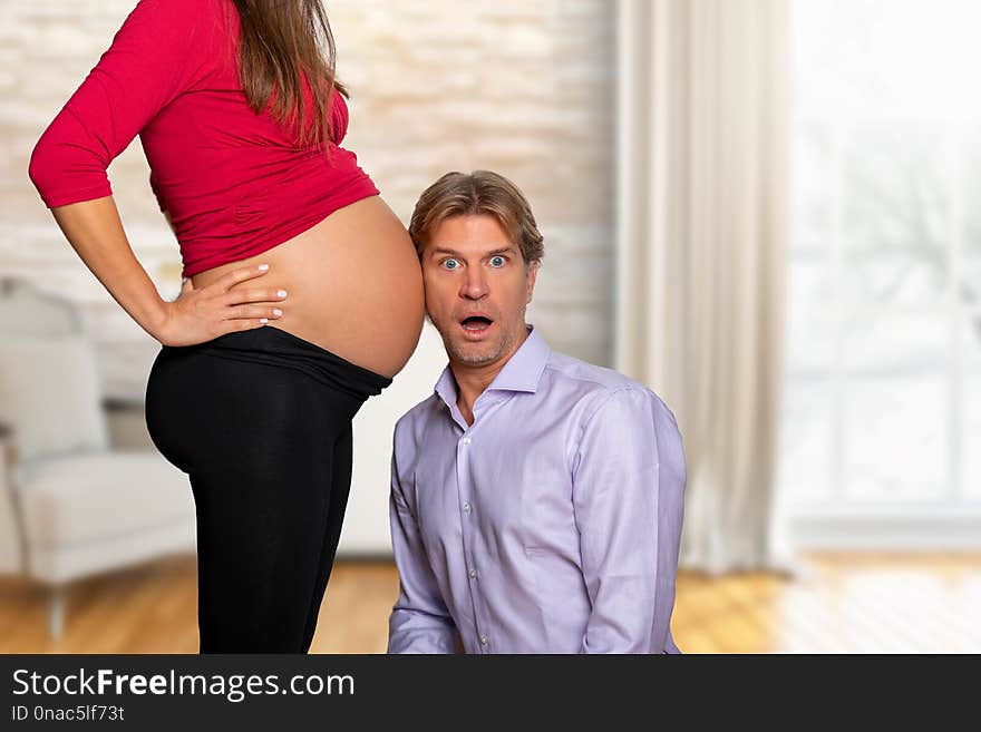 Excited, surprised men listens to the pregnant belly of his wife. Excited, surprised men listens to the pregnant belly of his wife