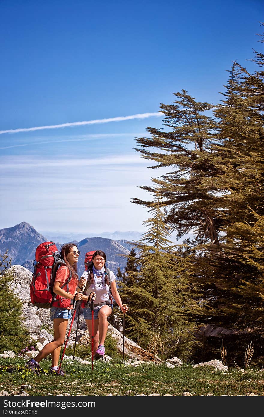 Summer hike in the mountains with a backpack and tent along the path to the top.