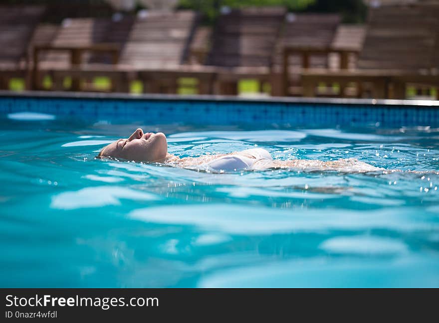 Vacation in a tourist resort. Woman swims in the pool.