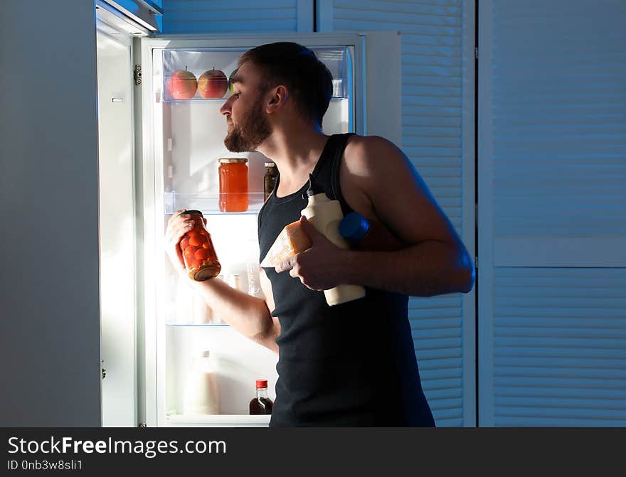 Man Taking Products Out Of Refrigerator In Kitchen