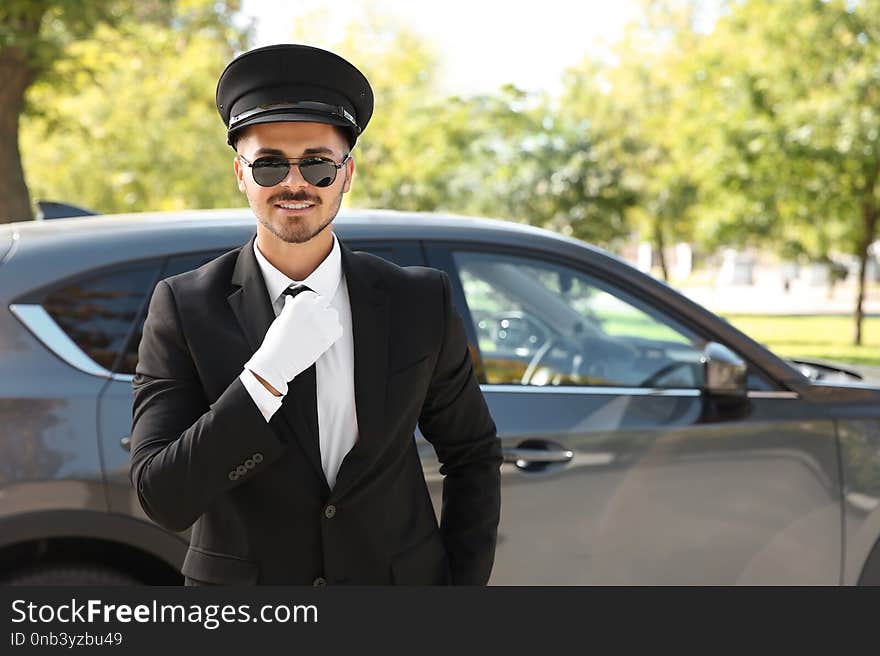 Young handsome driver standing near luxury car. Chauffeur service