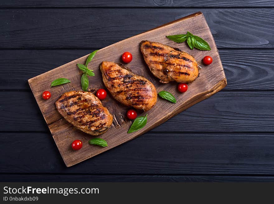 Grilled chicken breast fillet with basil and tomatoes . BBQ background