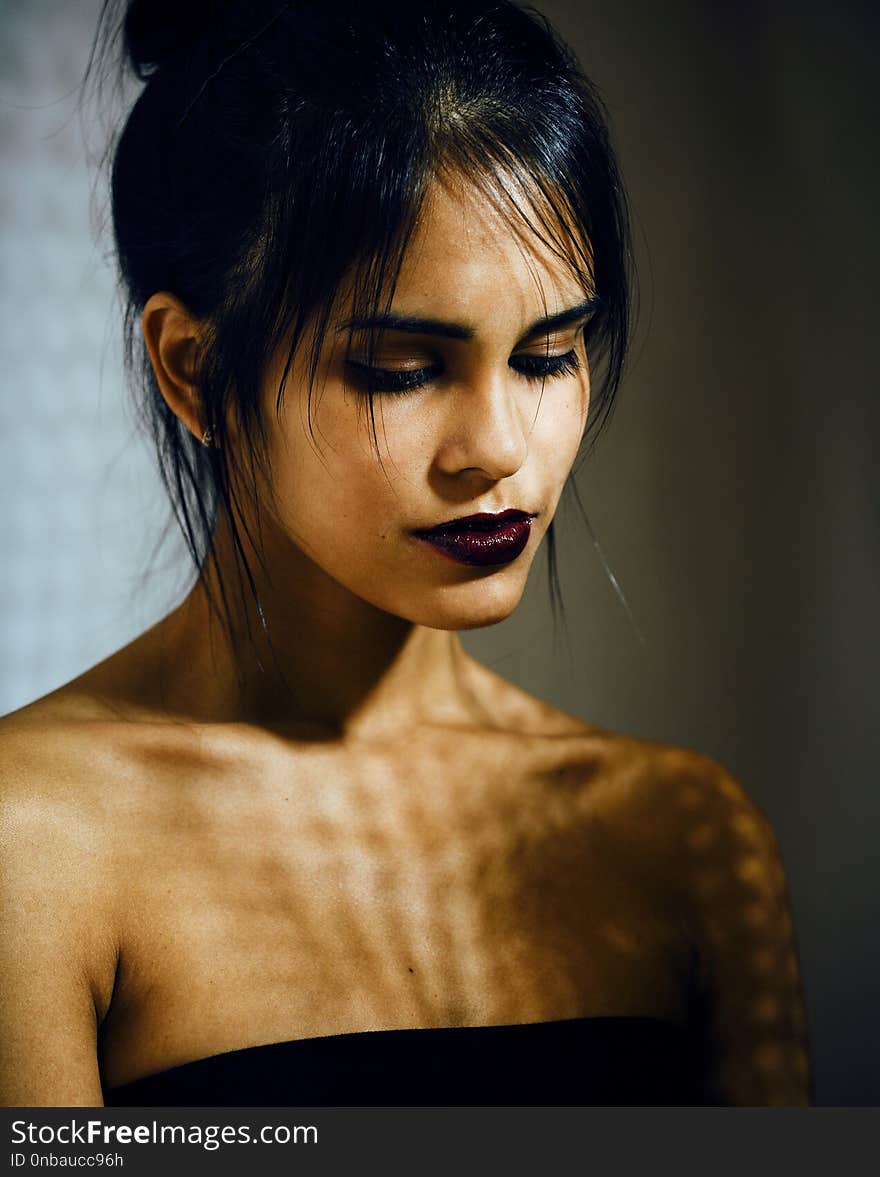 Pretty brunette woman with make up like demon at halloween, closeup scary background concept fashion