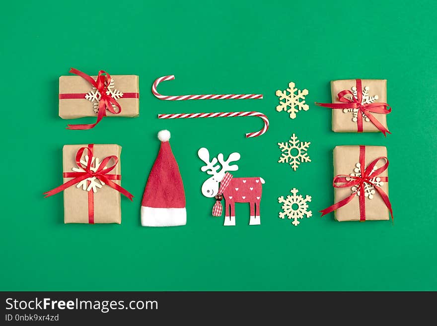 Christmas composition. Christmas decoration gifts, , Santa Claus hat , candy, snowflakes on green background.