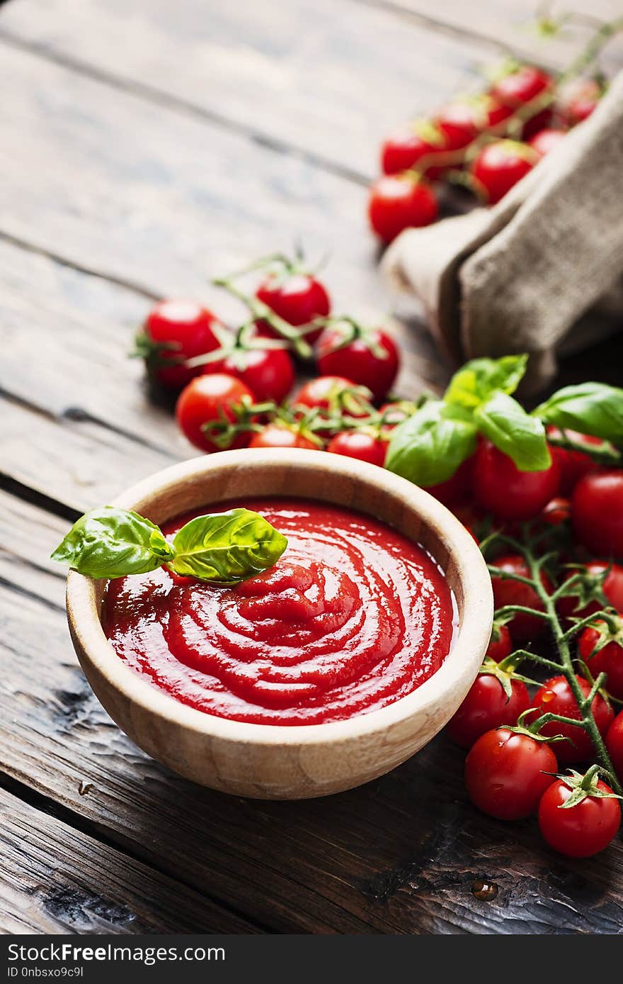 Bowl of tomato sauce and cherry tomatoes on the wooden table, selective focus