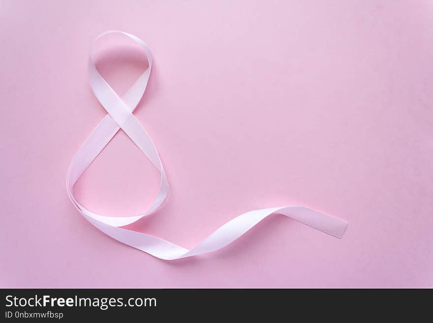 Rose gift celebration ribbon in 8 digit shape over pale pink background. Rose gift celebration ribbon in 8 digit shape over pale pink background