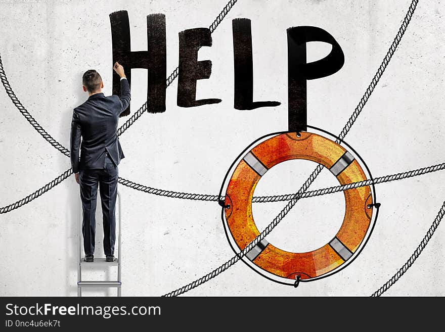 A back view of a man in suit standing on a ladder and writing the title `Help` on a wall with a painting of lifebuoy below. Business support. Assisting businesses. Getting help and valuable advice.