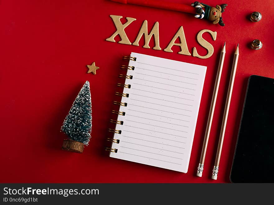 Christmas shopping list and mobile phone, Holiday planning red background, notebook and christmas decoration.