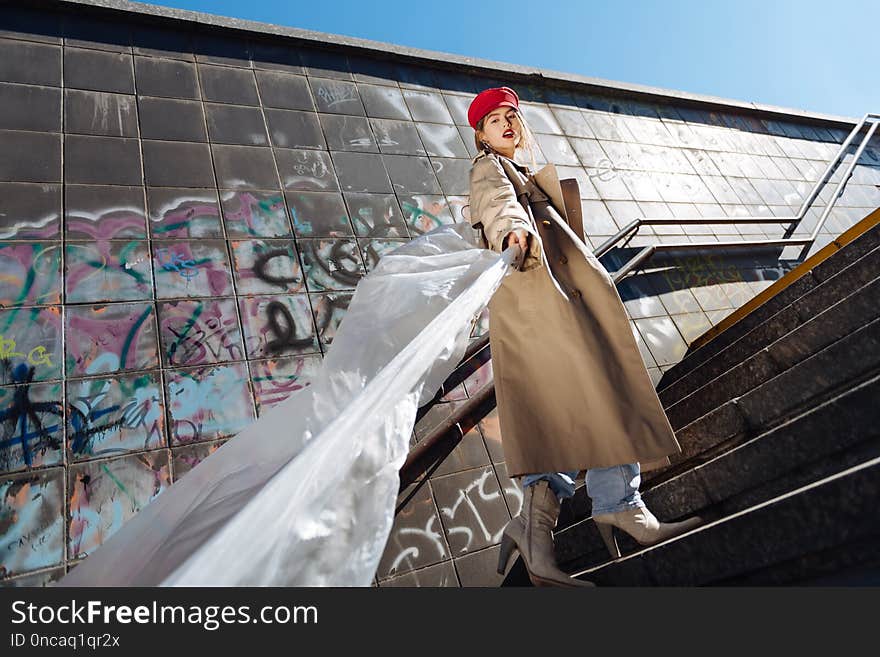 Fashion model. Stylish skinny fashion model posing wearing beige coat and red beret working for French magazine