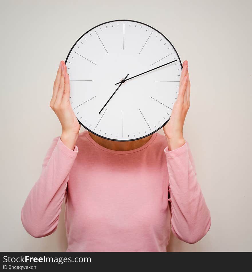 Girl covering her face from a clock. Woman hides from stress and deadline concept