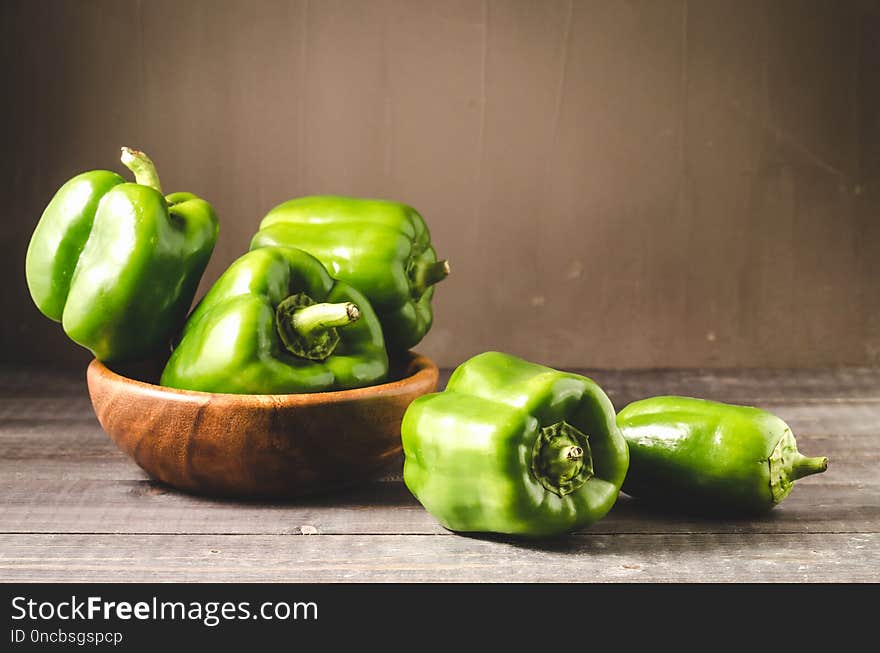 green organic paprika on wooden bowl/ Fresh green organic paprika on wooden bowl over dark wooden table. Copy space