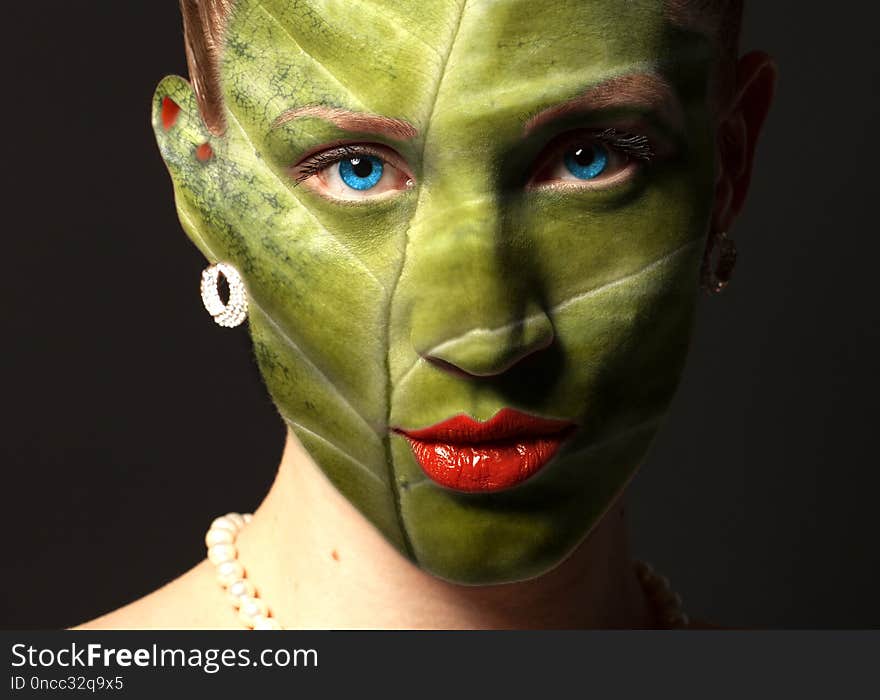 Woman face with leaf texture and blue eyes. Ecology concept.