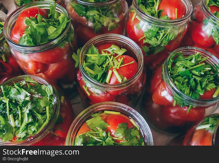 Fermenting vegetables with lots of greens in glass jars. Processing the harvest of tomatoes from home garden