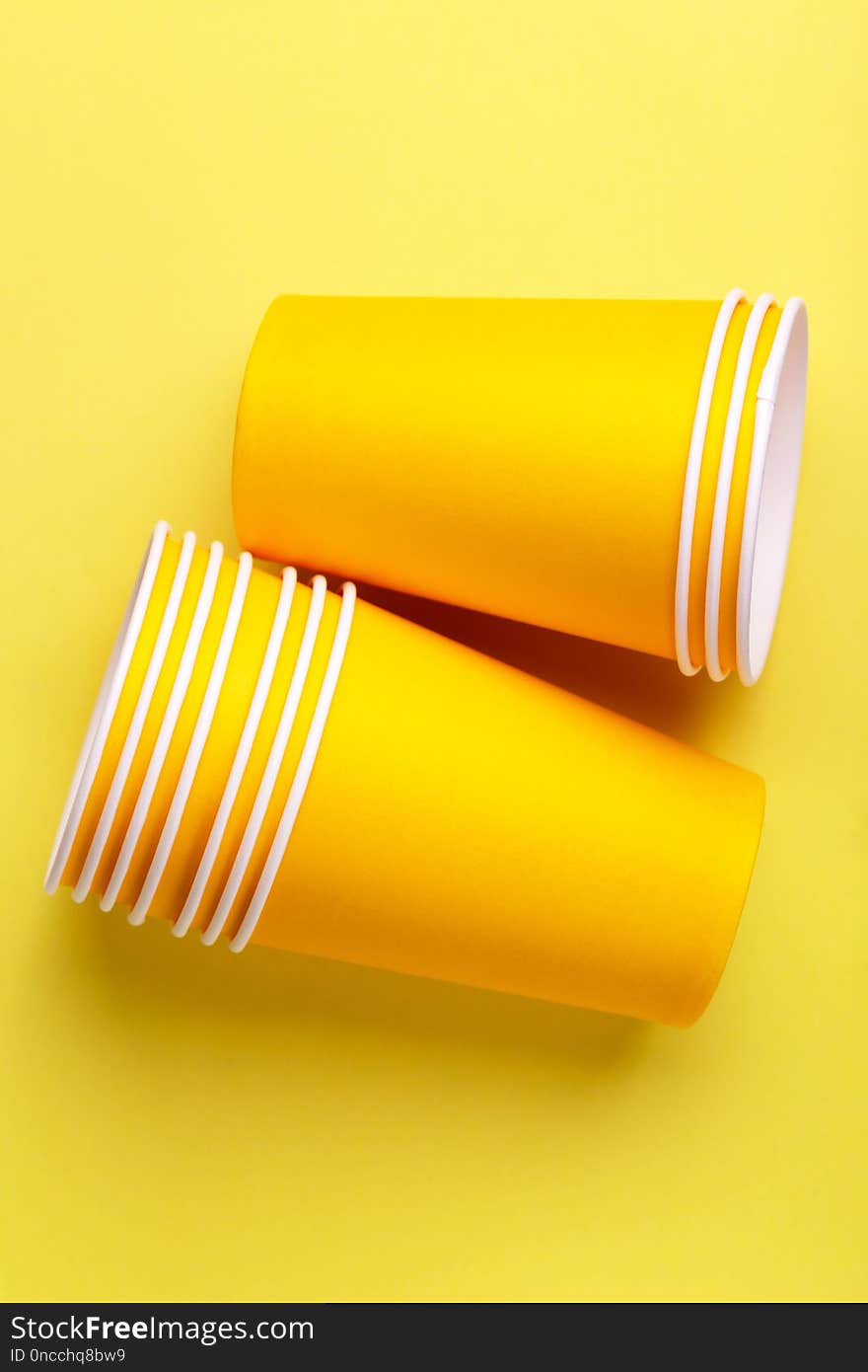 Recycling paper cups for drinks on bright yellow background.