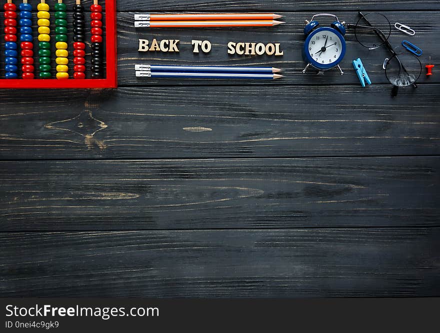 Back to school, education concept. set of stationery on the grey wooden background. scores, round glasses, pencils, clock