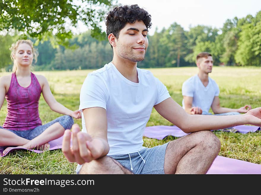 Man practicing yoga and meditating in summer in the nature