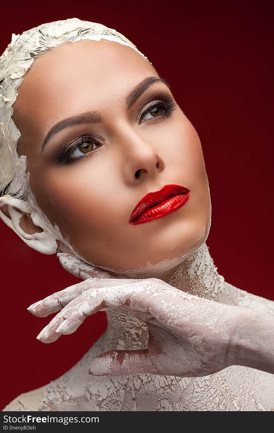 Beautiful woman in a clay mask on a red background. Beautiful woman in a clay mask on a red background