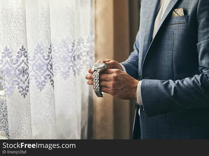 Businessman checking time on his wrist watch, man putting clock