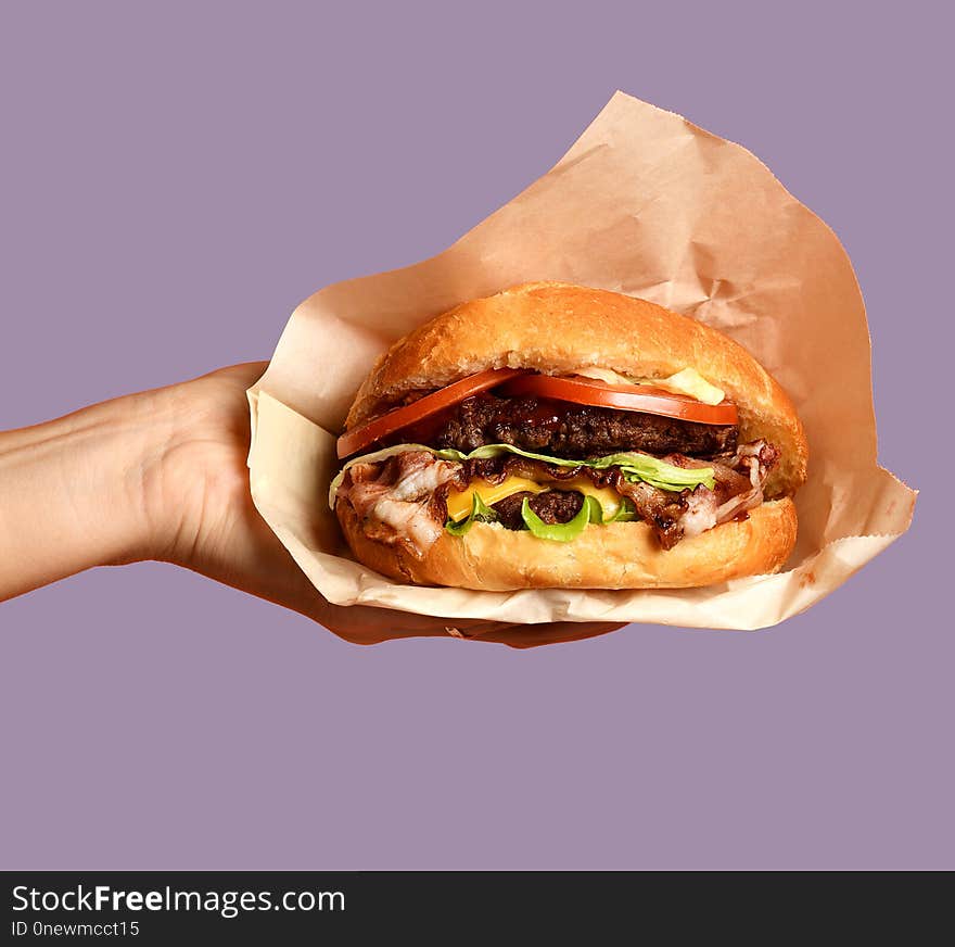 Woman hands hold big cheese burger barbeque sandwich with marble beef on purple