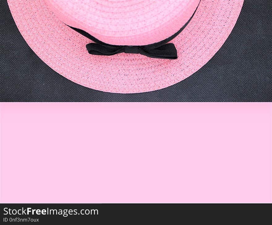 Pink hat with a black bow is lying on a black background. Free space for your signature