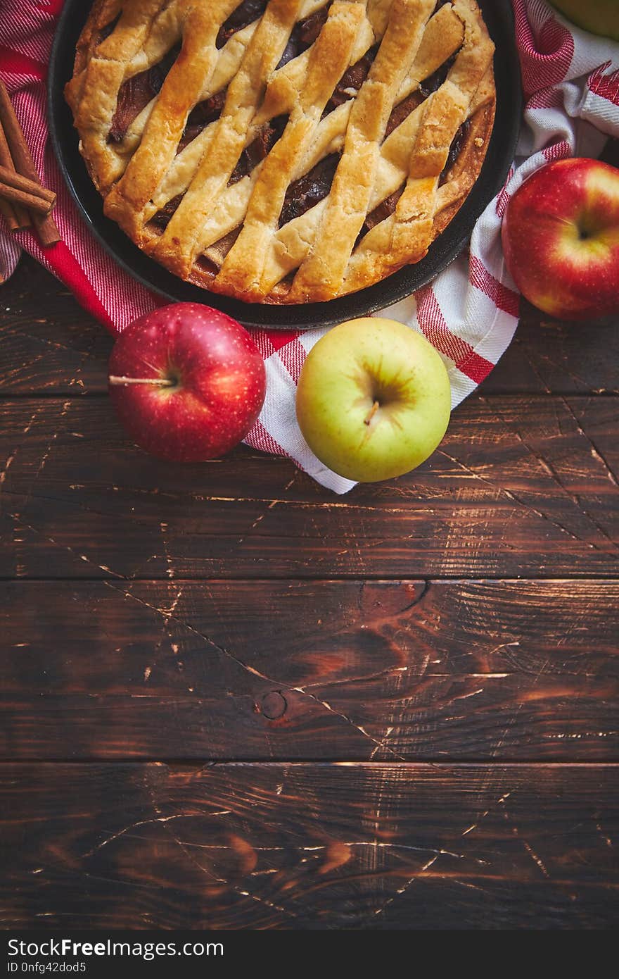 Homemade pastry apple pie with bakery products on dark wooden kitchen table