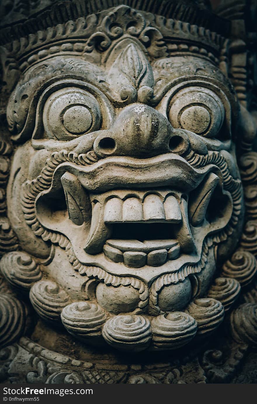 Closeup portrait of stone traditional sculpture art form incorporated into temples, which demonstrate the influences of Hindu Buddhist culture. Bali, Indonesia. Closeup portrait of stone traditional sculpture art form incorporated into temples, which demonstrate the influences of Hindu Buddhist culture. Bali, Indonesia