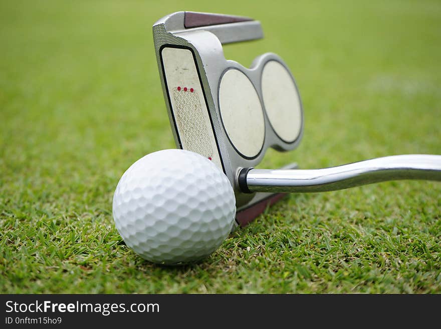 golf club and golf ball close up in grass field with sunset. Gol