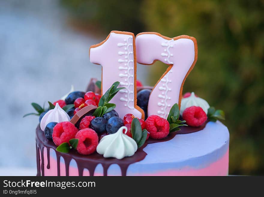 Beautiful birthday cake with the number seventeen, decorated with fresh berries and colorful cream