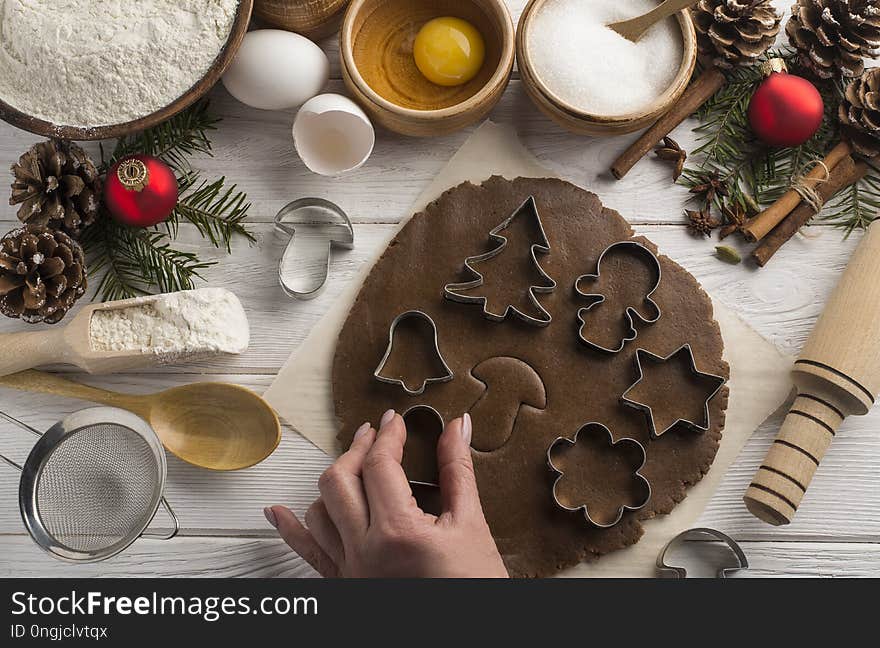 Girl`s hands cook holiday Christmas biscuits with decorative molds on a wooden white background. Top view. Girl`s hands cook holiday Christmas biscuits with decorative molds on a wooden white background. Top view.