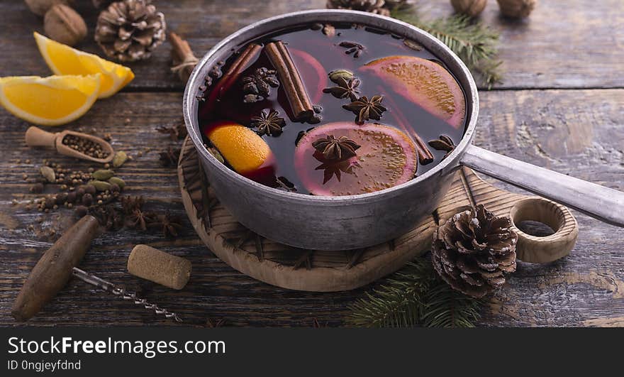 Traditional Cristmas hot mulled wine with species, honey, citrus fruits in a pan on wooden board on a rustic background. Traditional Cristmas hot mulled wine with species, honey, citrus fruits in a pan on wooden board on a rustic background.