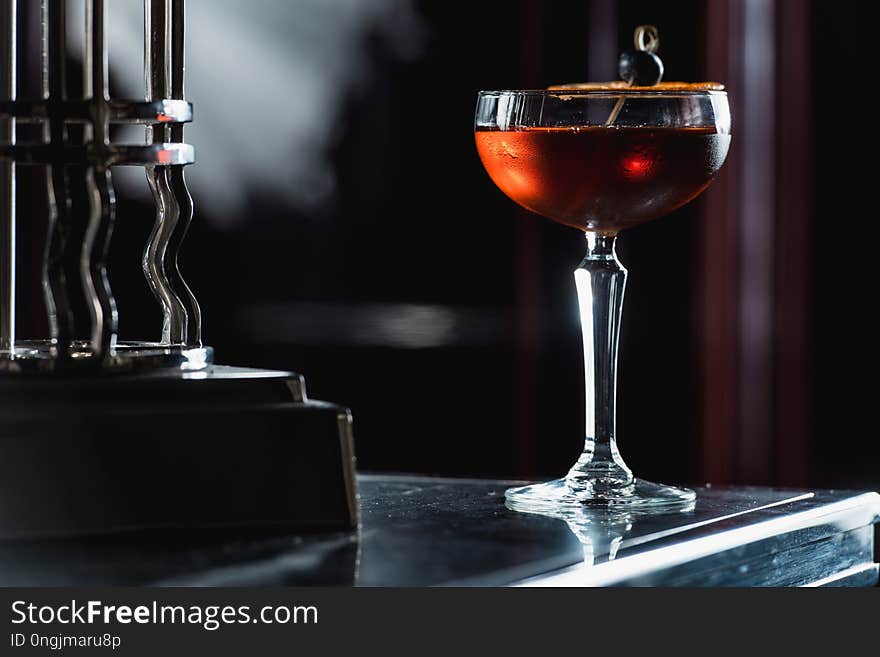 The Boulevardier Cocktail with orange chips on top. On a bar desk