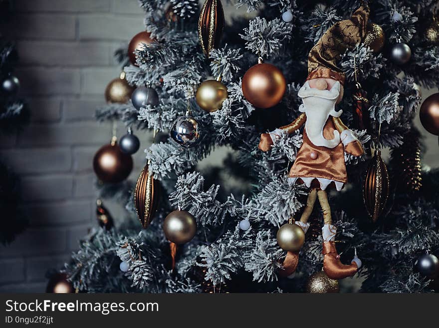 Close up of pine decorated for Christmas gold checkered bows and ribbons. Traditional handmade decoration covered with snowflakes. Concept of Christmas and New Year holidays. Winter season.