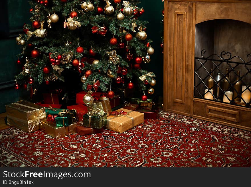 Christmas tree with red checkered bows and ribbons and many gifts and box near. Traditional handmade decoration covered with snowflakes. Concept of Christmas festive mood at home near fire place. Christmas tree with red checkered bows and ribbons and many gifts and box near. Traditional handmade decoration covered with snowflakes. Concept of Christmas festive mood at home near fire place.