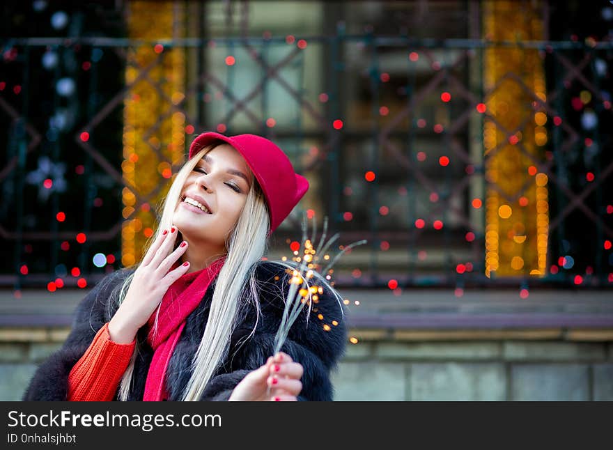 Adorable blonde model celebrating New Year with sparklers at the blurred city lights. Empty space. Adorable blonde model celebrating New Year with sparklers at the blurred city lights. Empty space