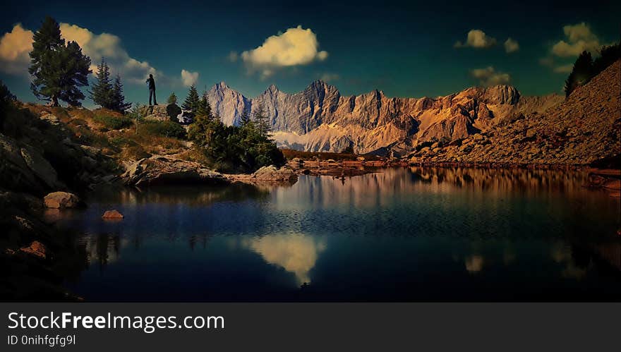 Traveller man with backpack enjoying beautiful view in mountain, blue sky, positive emotions,travelling lifestyle.Lake,stones,,trees,blue sky,peaks.Reflexion on water,panoramic composite photo.Alps .