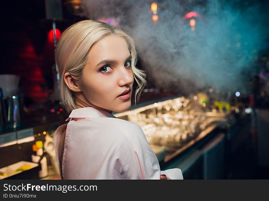 Portrait of a girl in a night bar, behind the counter.