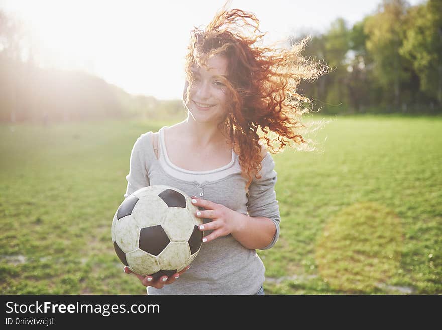 Young redhead girl in casual player in soccer stadium at sunset