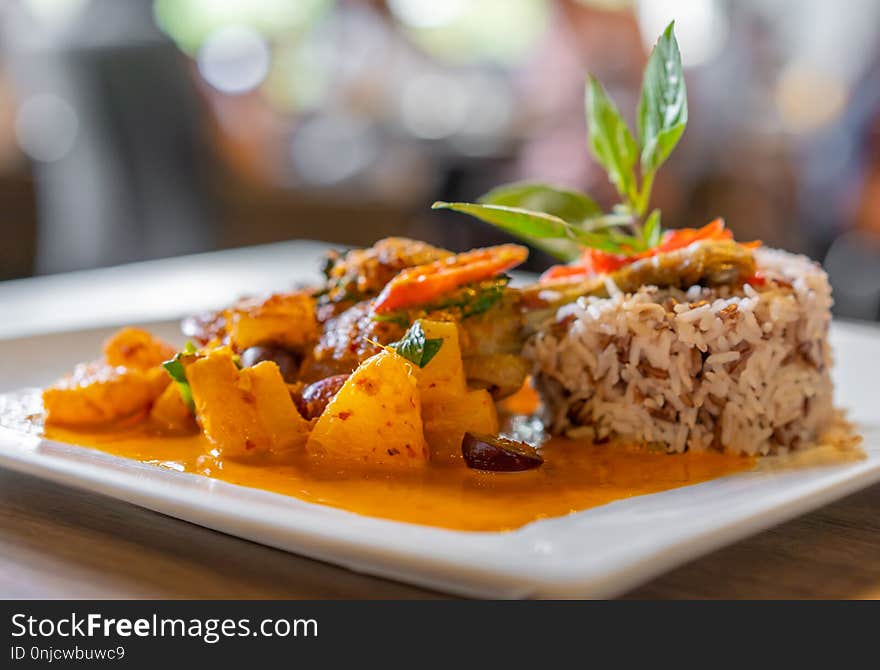 Duck confit with red curry served with brown rice on a plate