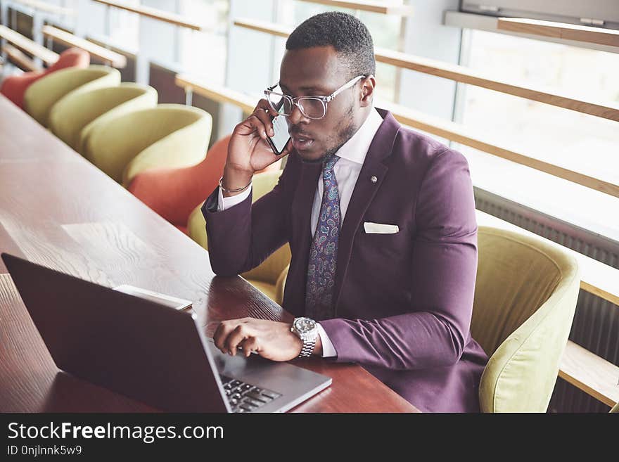 A beautiful stylish African American businesswoman wearing a suit uses his laptop while working