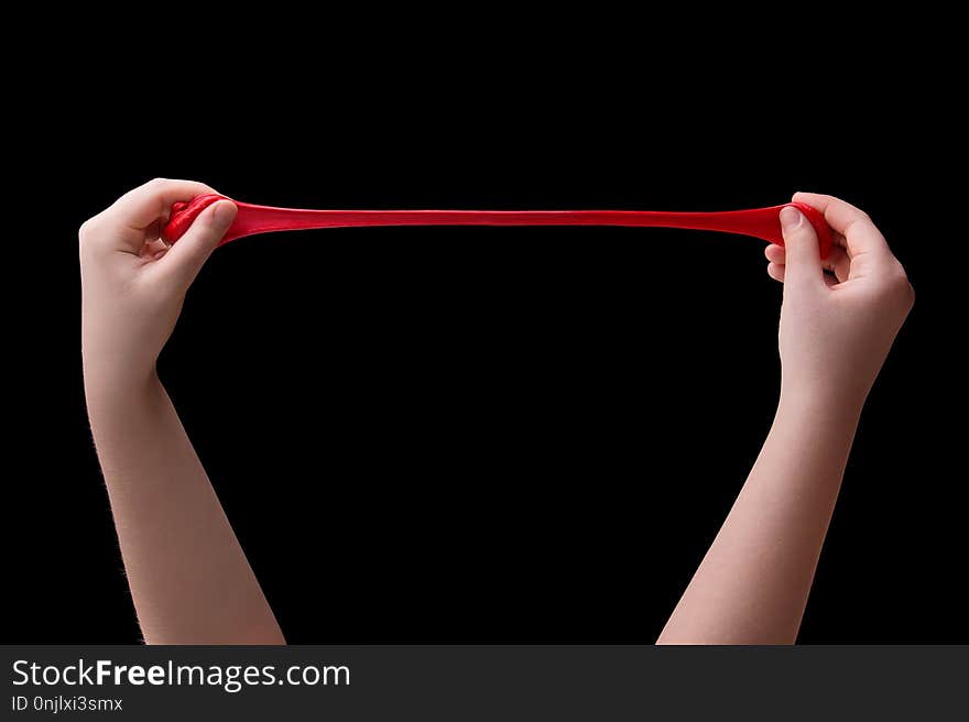 Red slime in the hands of a child on a black background. Red slime in the hands of a child on a black background