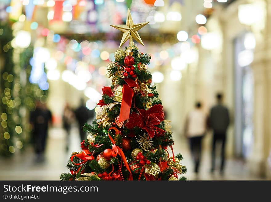 Photo of decorated Christmas tree with gold and red balls, star in store.